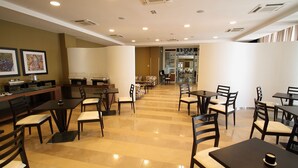 A spacious dining area with multiple tables and chairs, a kitchen area with a counter and appliances, and a view into a dining room through a glass partition. - Tenuta Inagro (San Severo)