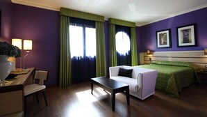 A hotel room with a bed, a sofa, a desk, and a chair.