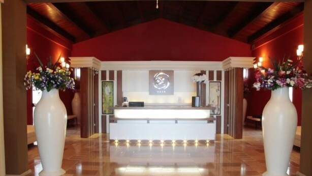 A reception area with a reception desk, two large vases with flowers, and a logo on the wall. - Tenuta Inagro (San Severo)