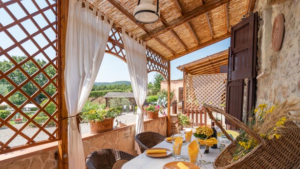 A terrace with wicker furniture, a table set for dining, and potted plants.