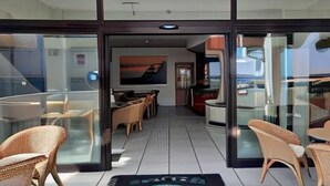 A modern interior with glass doors, wicker furniture, and a central seating area. - Hotel Giada (Silvi)