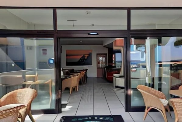 A modern interior with glass doors, wicker furniture, and a central seating area. - Hotel Giada (Silvi)