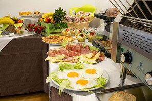 Un buffet proposant une variété de plats, notamment des œufs, de la viande et des fruits.
