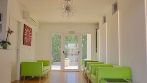 Een receptiezone met groene zitplaatsen, een kroonluchter en een deur die naar buiten leidt.