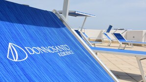 Een blauwe loungestoel met de tekst 'DONNOSANTO RESIDENCE' erop.