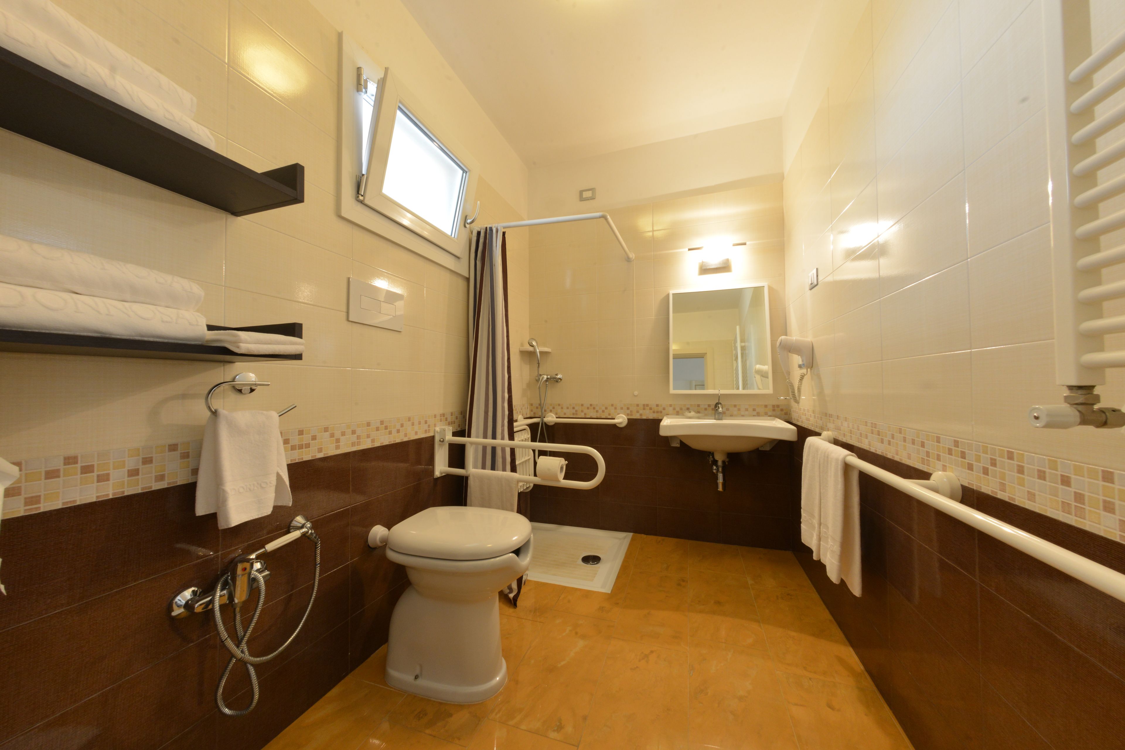 A bathroom with a toilet, shower, sink, and towel racks.