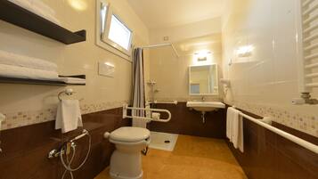 A bathroom with a toilet, shower, sink, and towel racks.