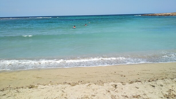 Een strand met helder turquoise water en een zandstrand.