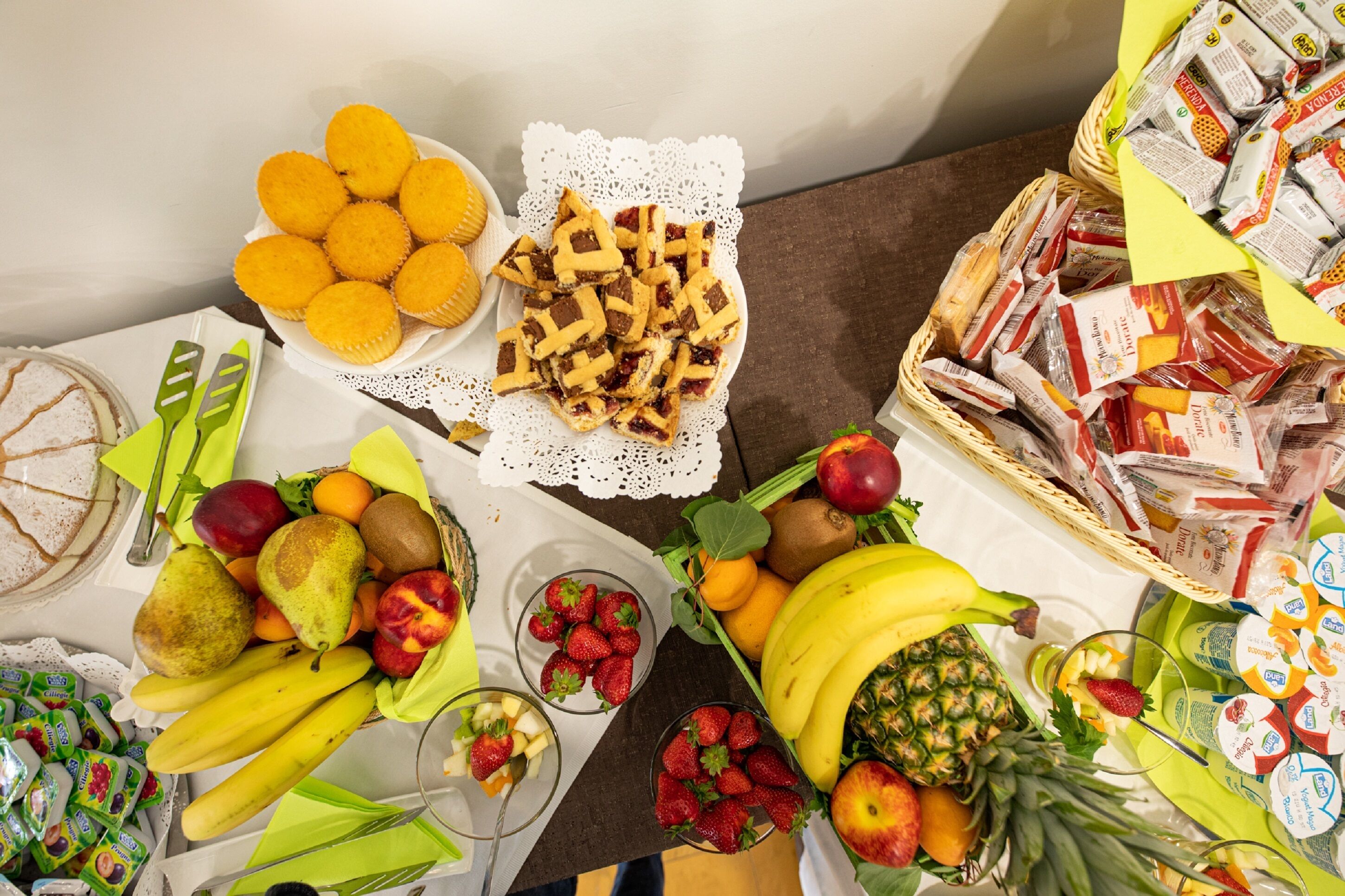 Ein Tisch mit verschiedenen Speisen, darunter Obst, Gebäck und verpackten Waren.