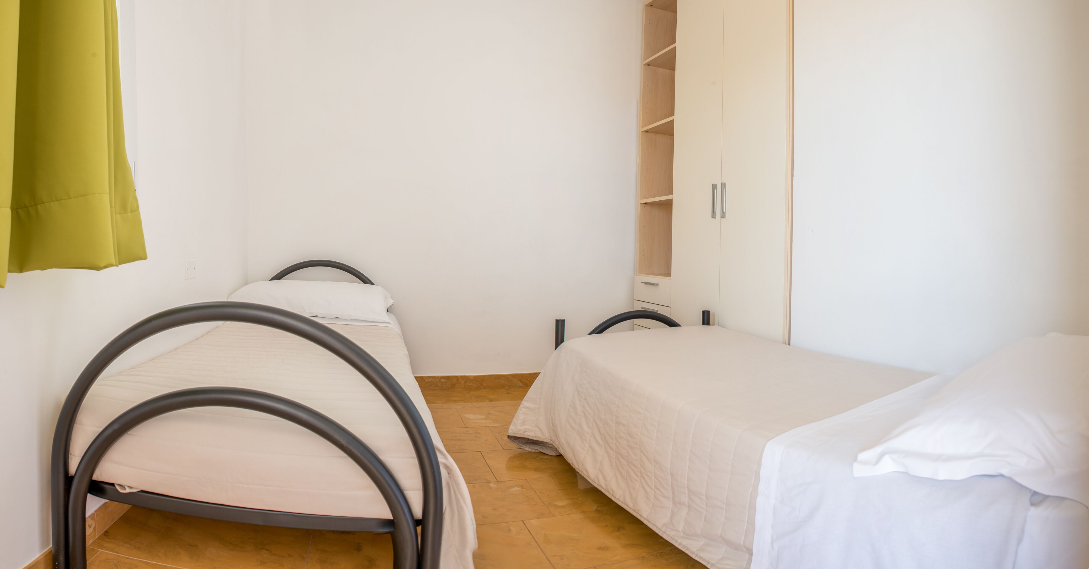 A small, clean room with two single beds and a wardrobe.