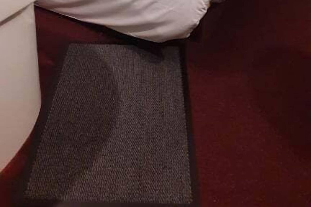 Une chambre avec un lit superposé, un lit simple, une table ronde blanche et un tapis gris.