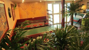 Un restaurante con una mesa verde, taburetes rojos y un mapa del mundo en la pared.