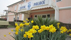 Un hotel llamado 'Quick Hotel Palace' con un cartel sobre la entrada.