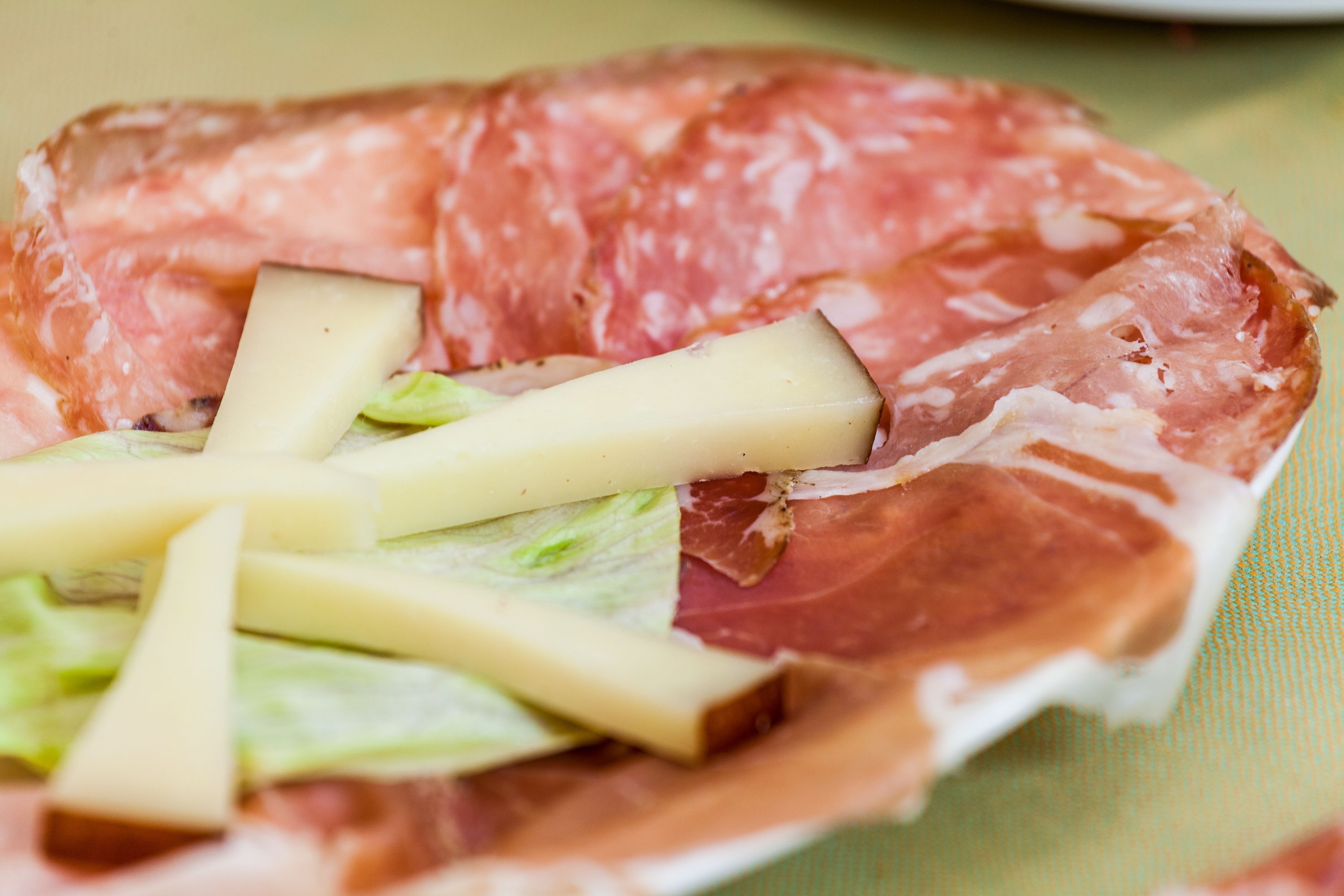 Un piatto di salumi, formaggio e lattuga.