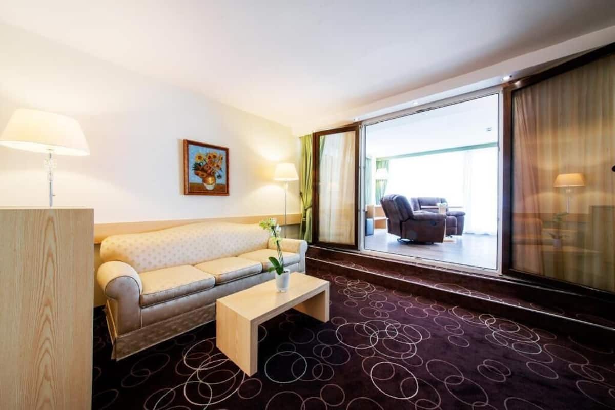 Une chambre d’hôtel avec un canapé, une table basse, un tableau et une vue sur l’extérieur.