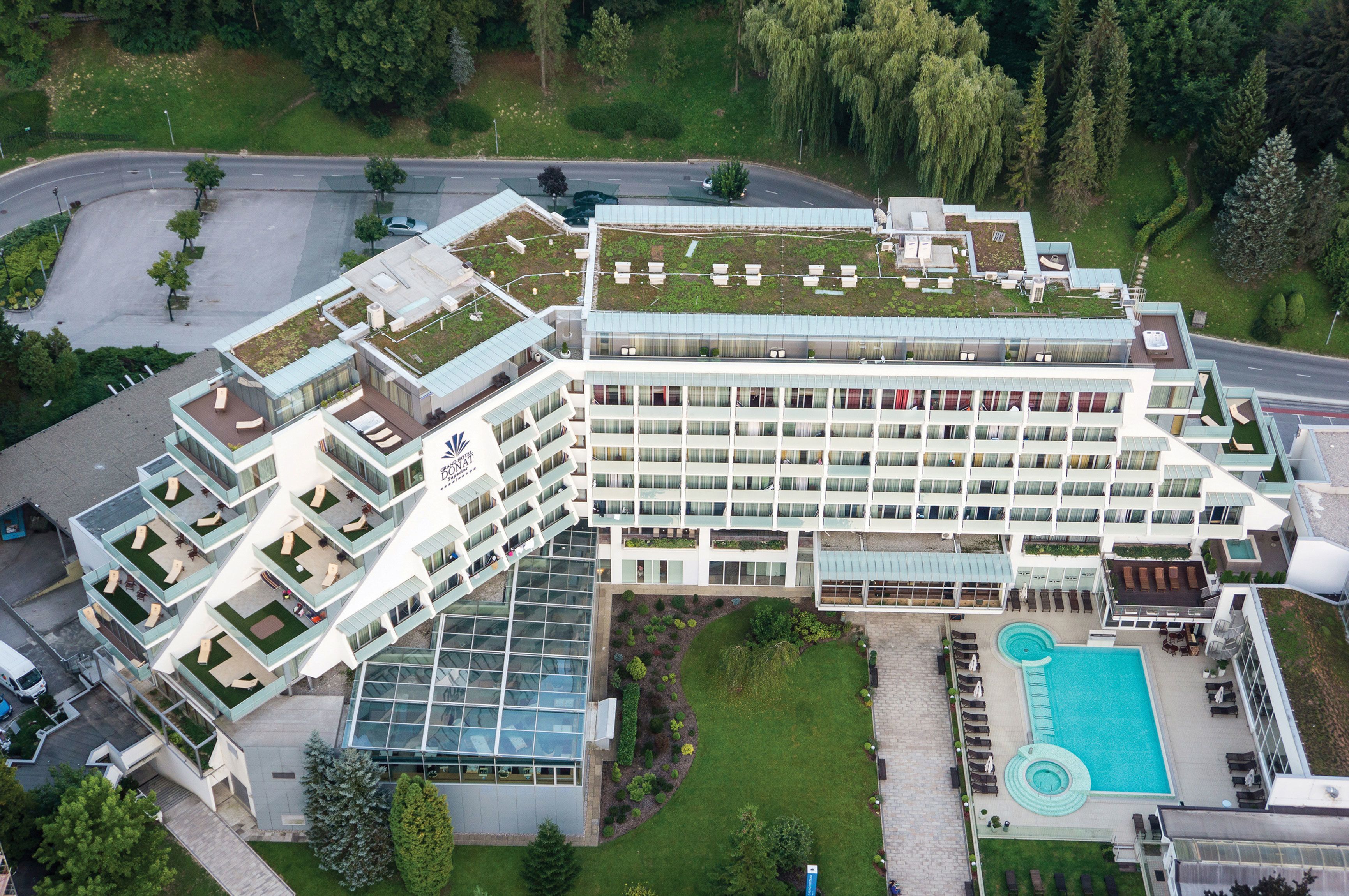 Un hotel moderno con varios pisos, un jardín en la azotea y una piscina.