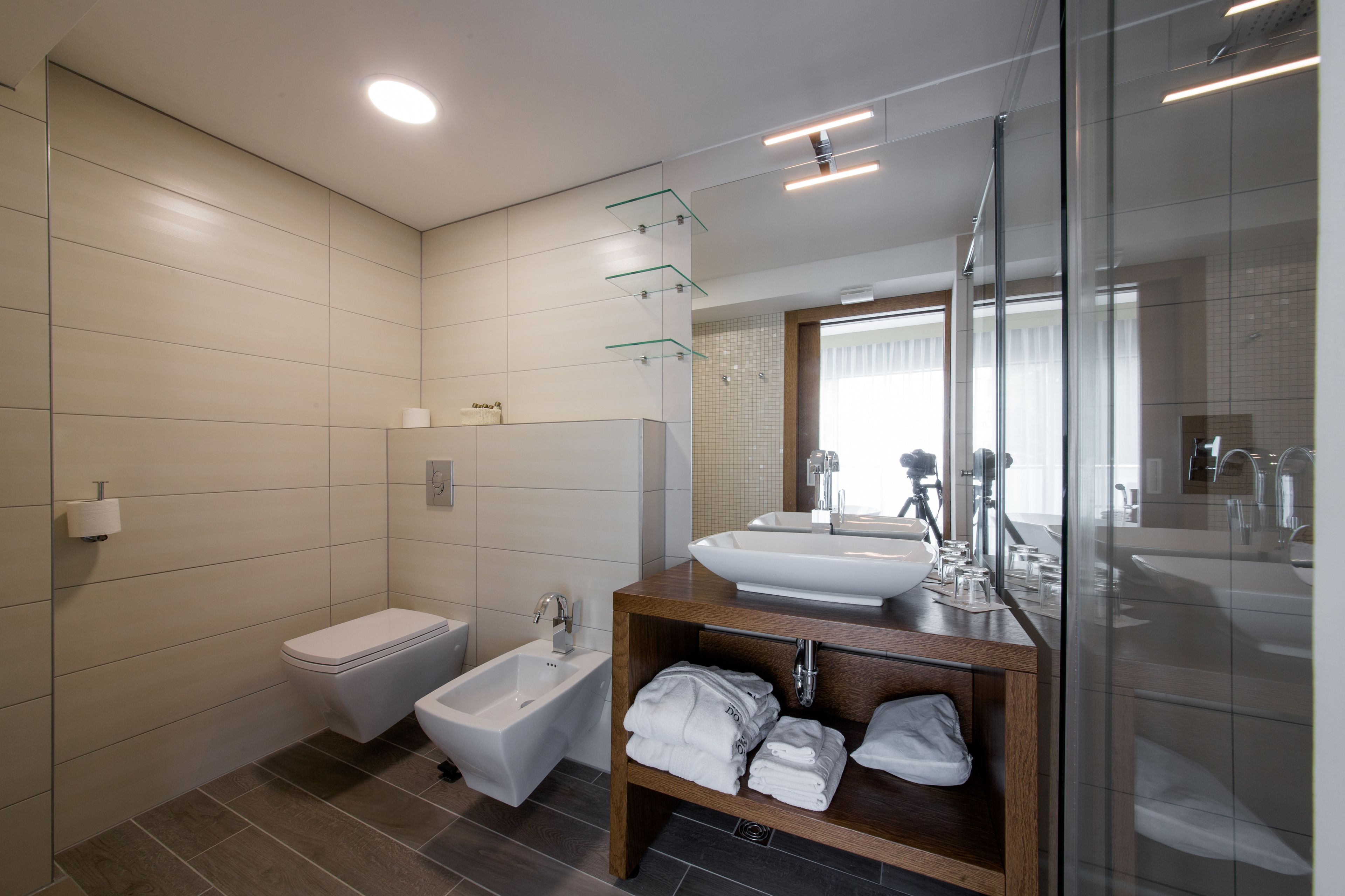 A modern bathroom with a bidet, a sink, and a glass shower enclosure.