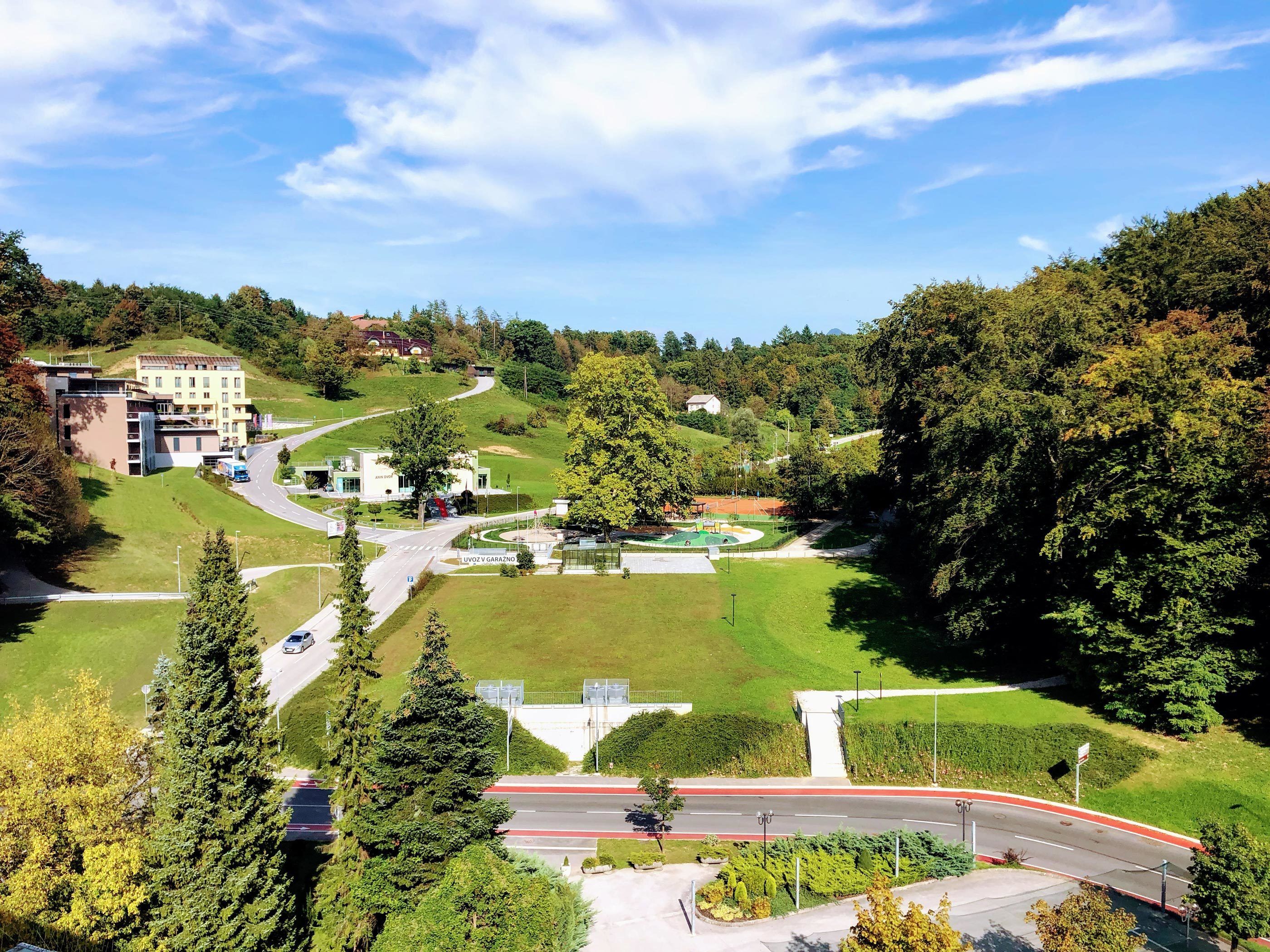Un ensemble immobilier moderne composé de plusieurs bâtiments, entouré d’une végétation luxuriante et bordé d’une route sinueuse.