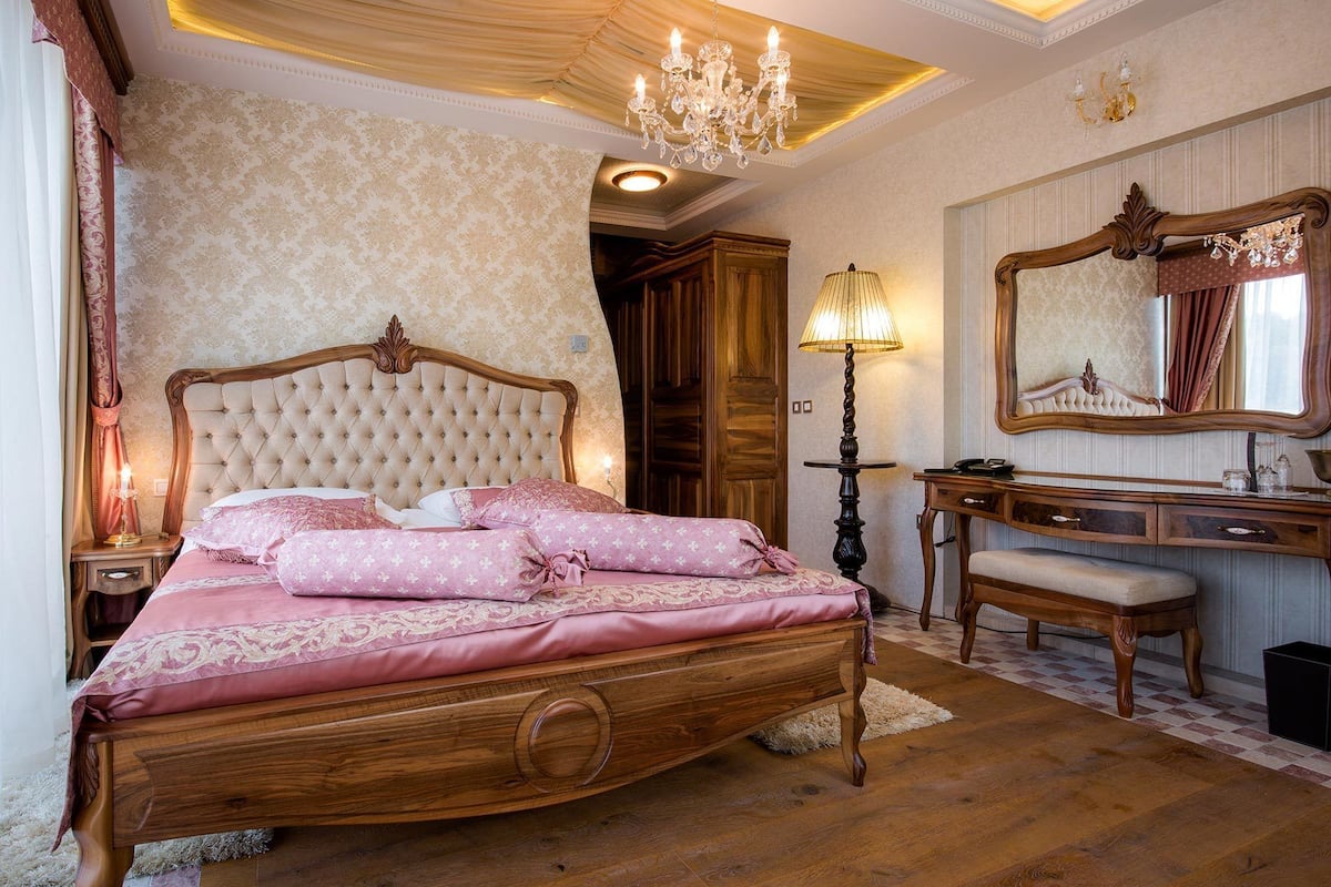 Une chambre à coucher avec un grand lit, une coiffeuse avec un miroir et un lustre.