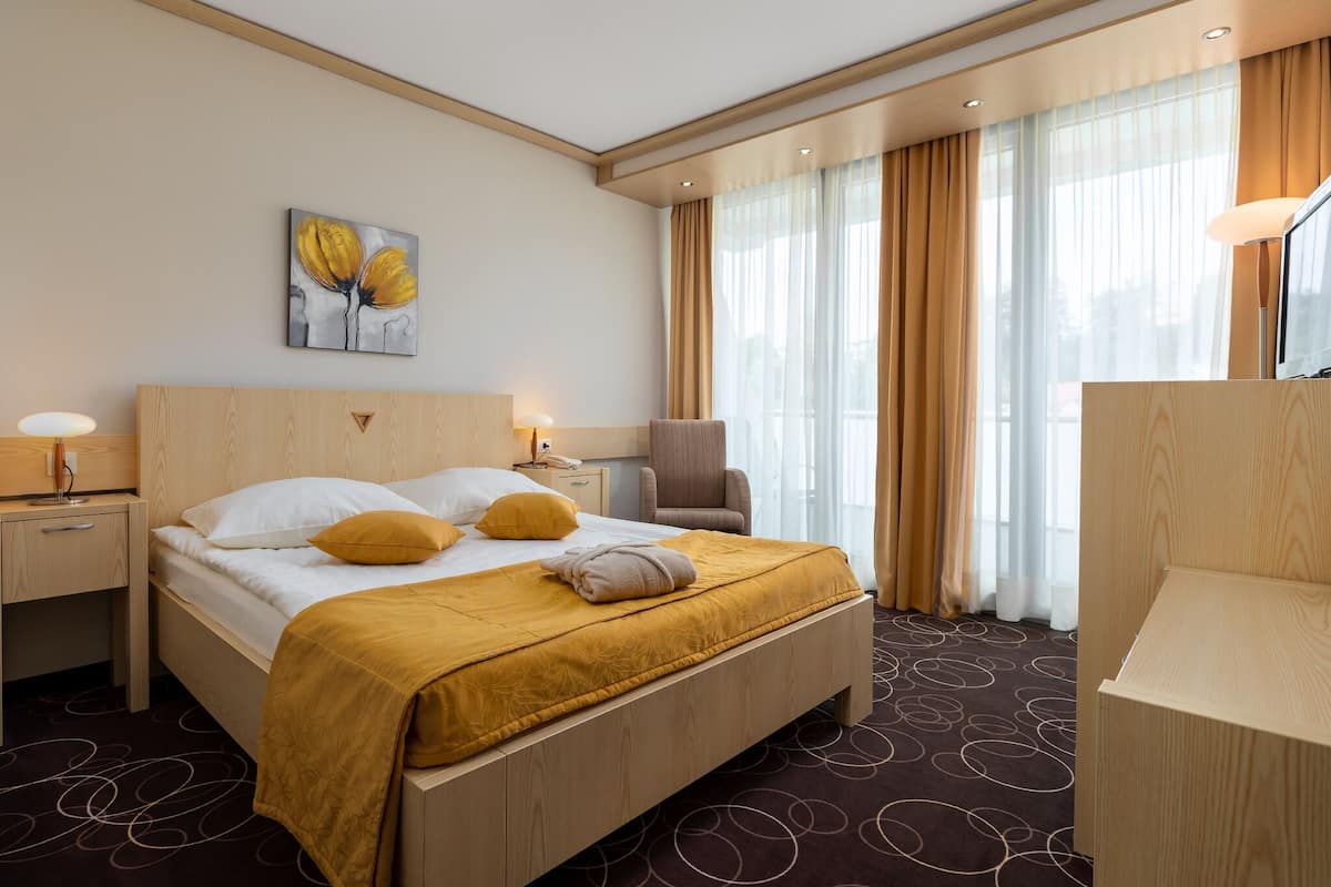 Une chambre d’hôtel avec un lit, une chaise, un bureau et un tableau au mur.