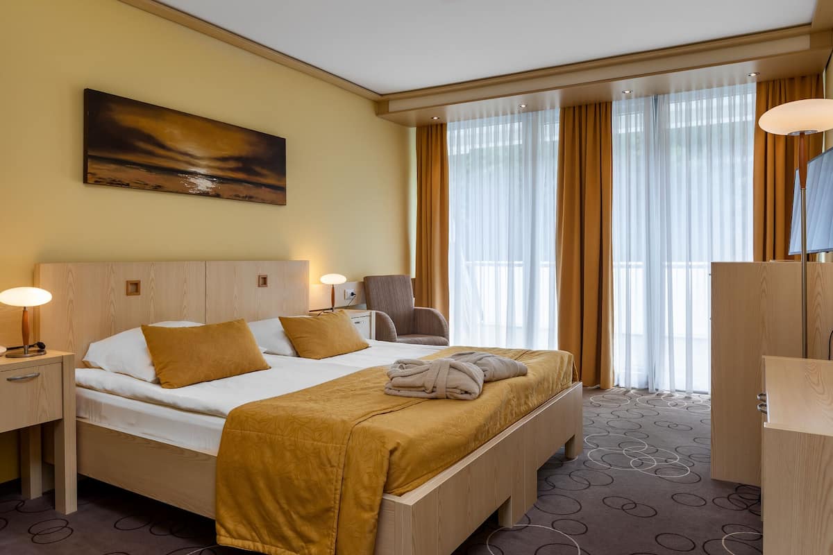 Une chambre d’hôtel avec un lit, une chaise, un bureau et un tableau au mur.