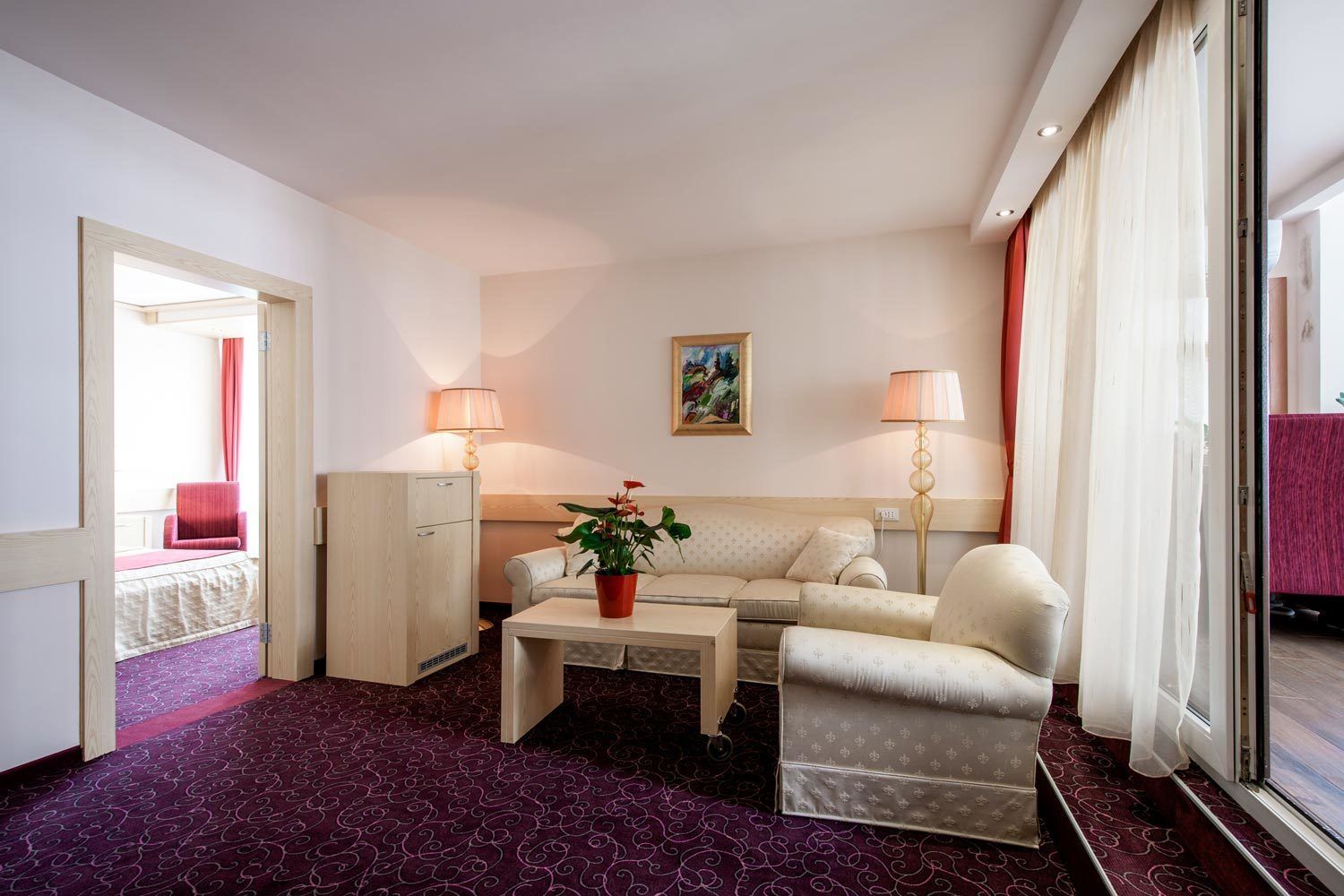 Ein Hotelzimmer mit einer Couch, einem kleinen Tisch mit Pflanze, einer Lampe und einem Bild an der Wand.