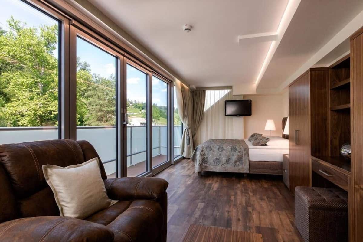 Une chambre d’hôtel dotée d’une grande fenêtre, d’un lit, d’une télévision et d’un coin salon.