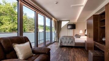 Quarto de hotel com uma janela grande, cama, televisão e área de estar.