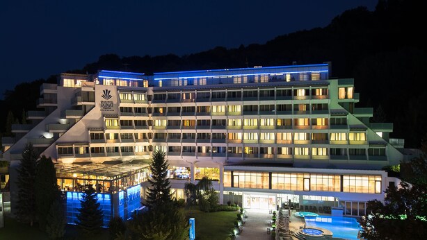 Een meerlaags hotel met een modern design, inclusief een zwembad en een goed verlichte gevel.