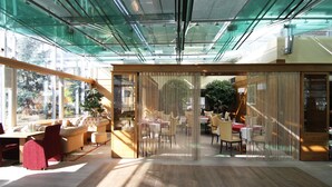 Een modern interieur met glazen plafonds, houten meubels en een plantenhoek.