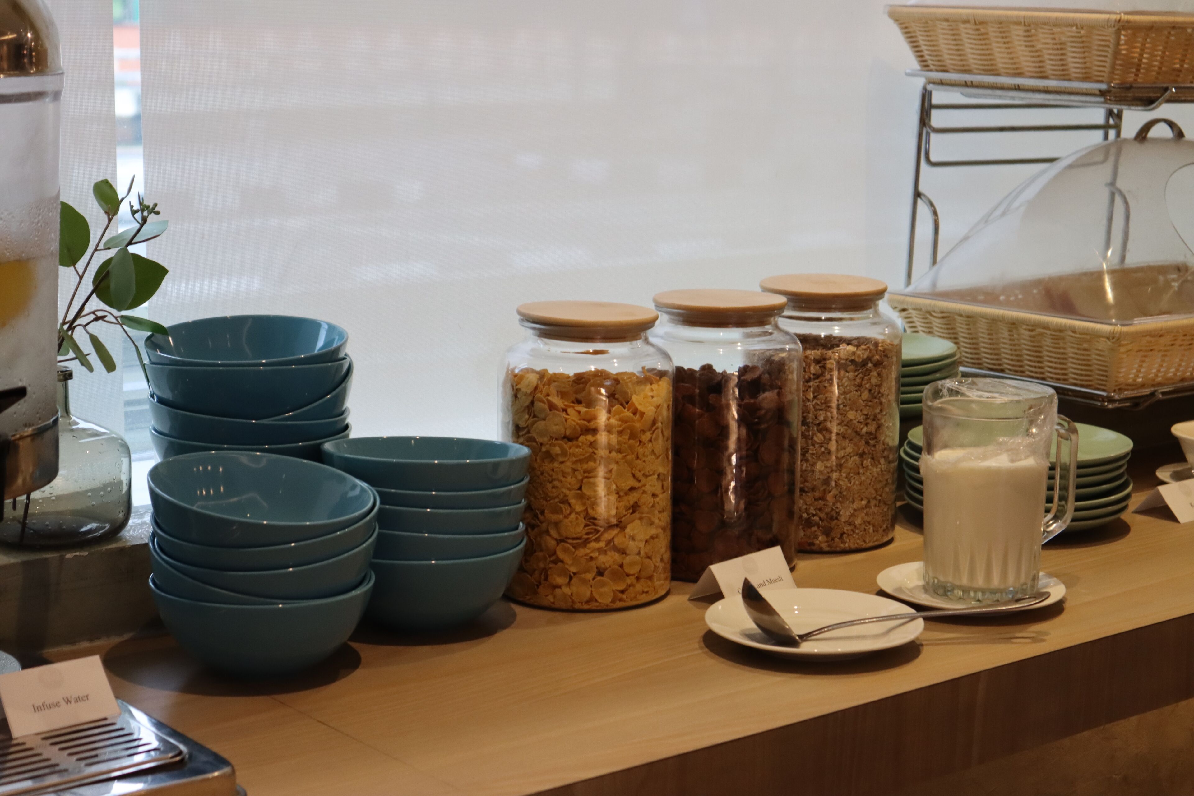 A buffet setup with blue bowls, jars of granola, and a milk pitcher.