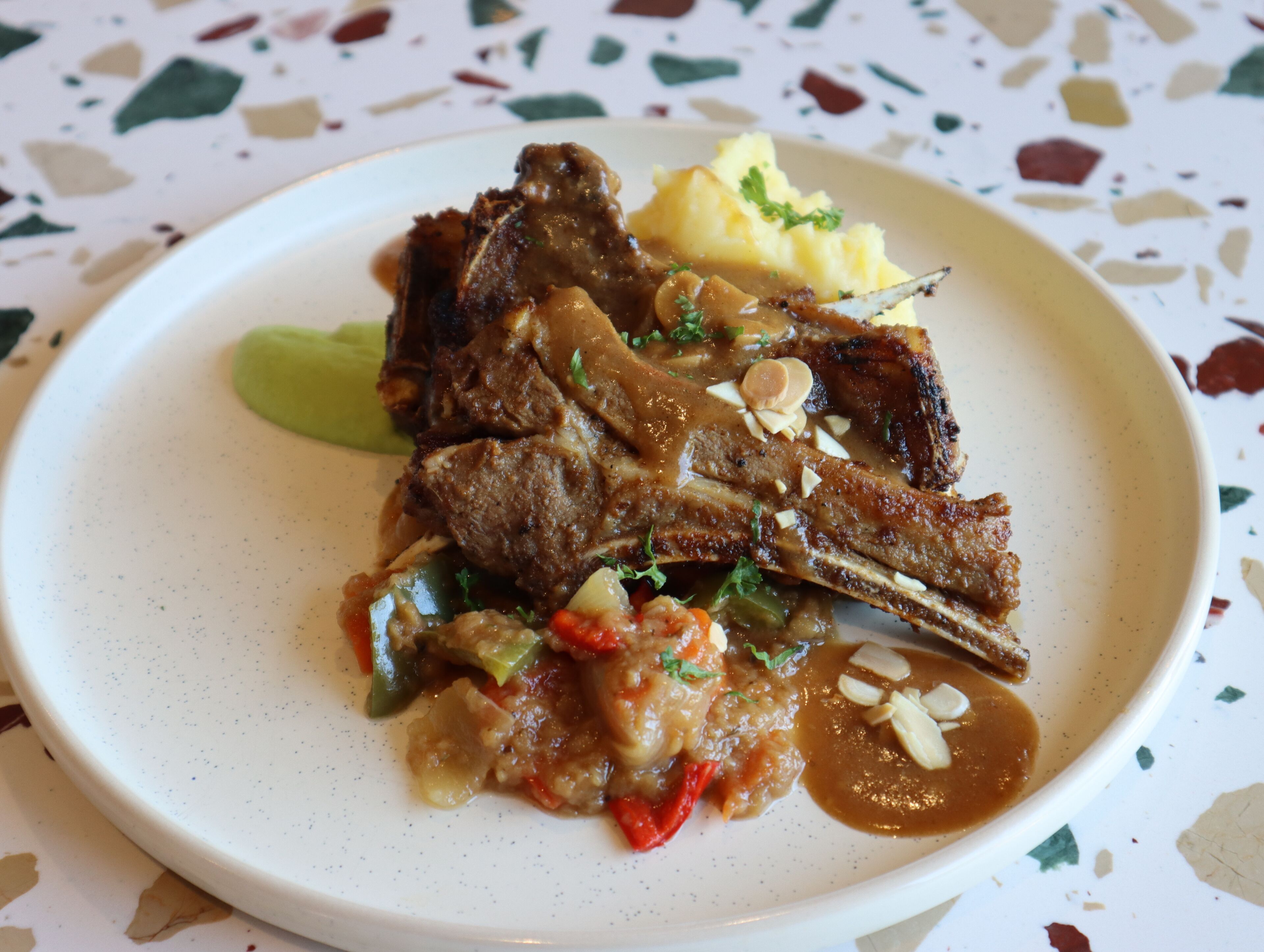 A plate of food with meat, vegetables, and a side of mashed potatoes.