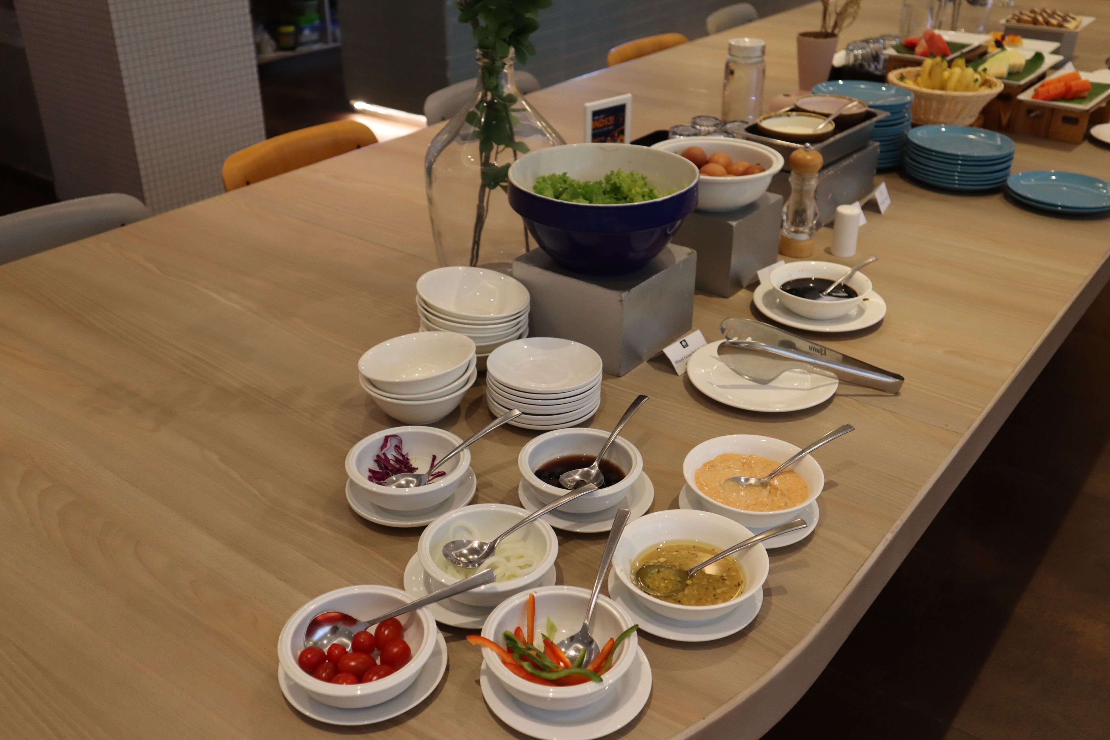 A buffet table with various food items and condiments.