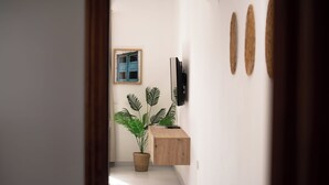 Een hal met een houten kast, een potplant en een ingelijst beeld aan de muur.