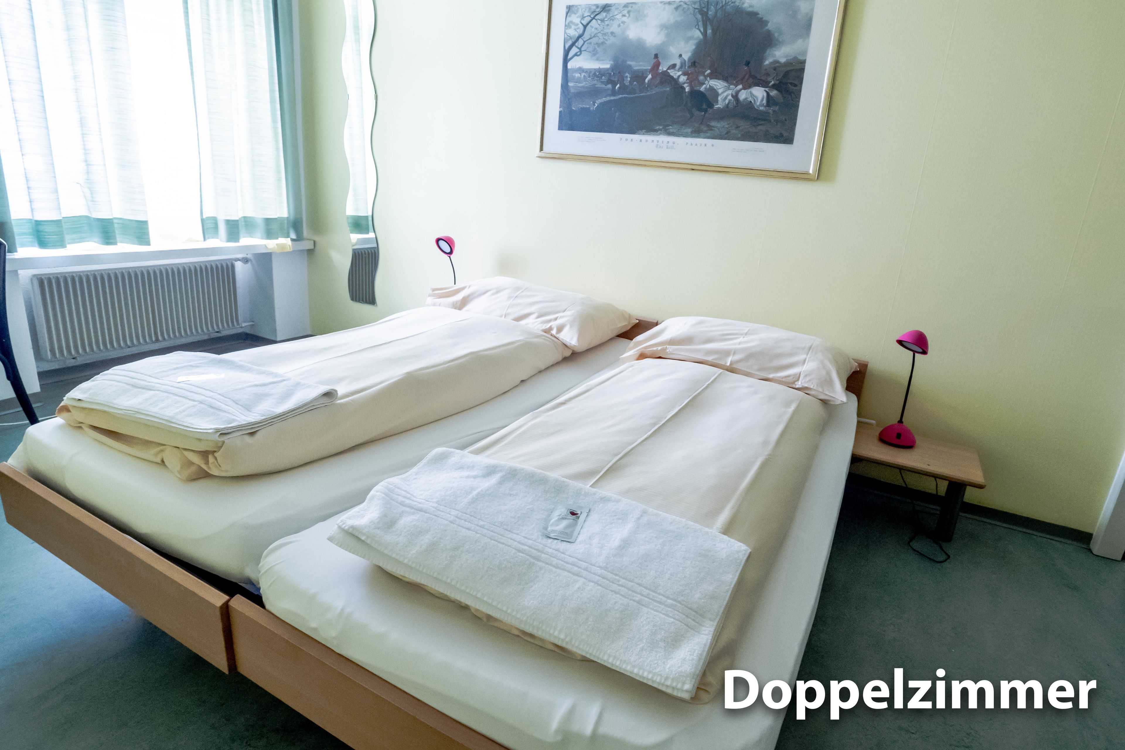 Habitación doble con cama, mesita de noche, lámpara y un cuadro en la pared.