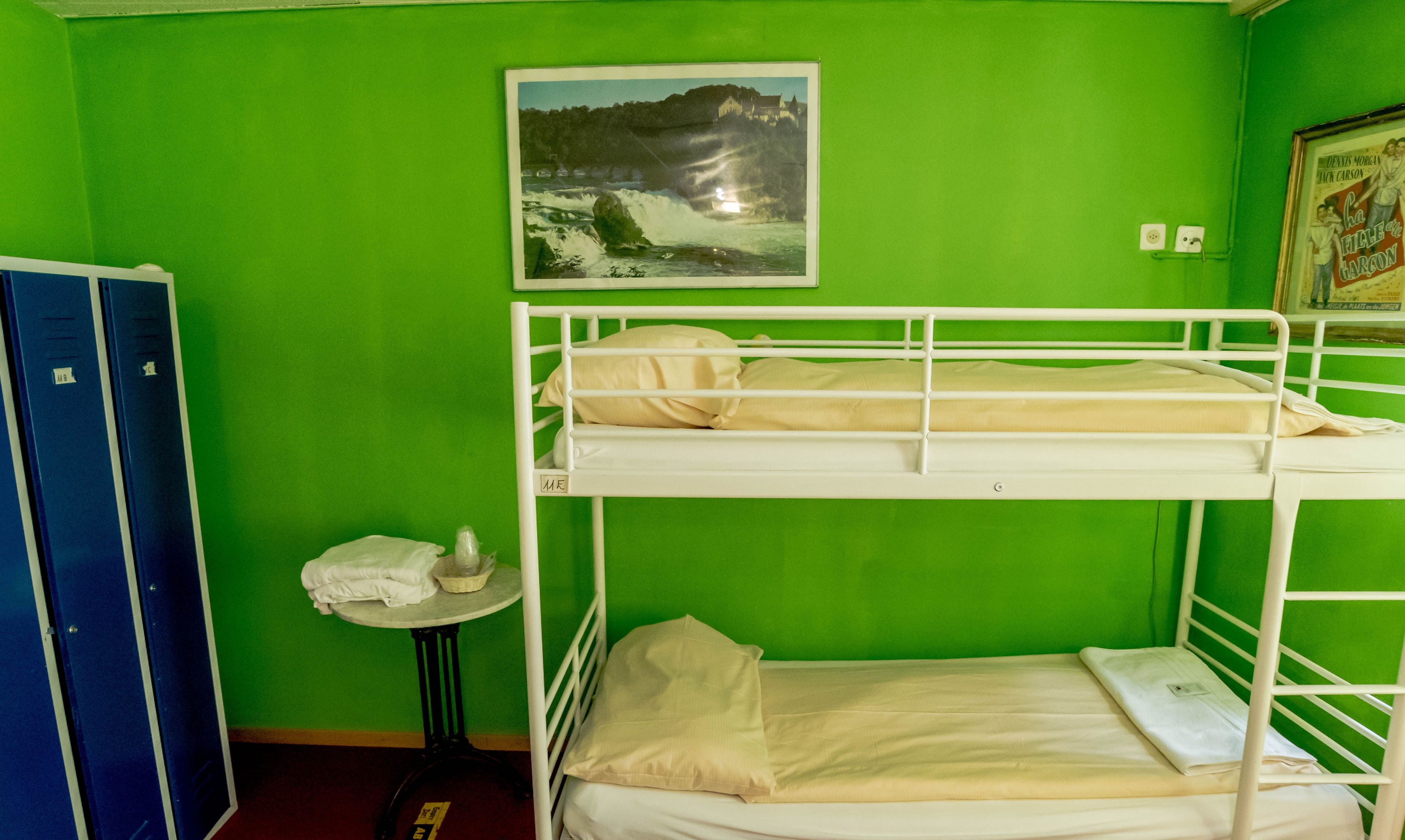 A bunk bed room with green walls, a framed picture of a castle, and a poster on the wall.