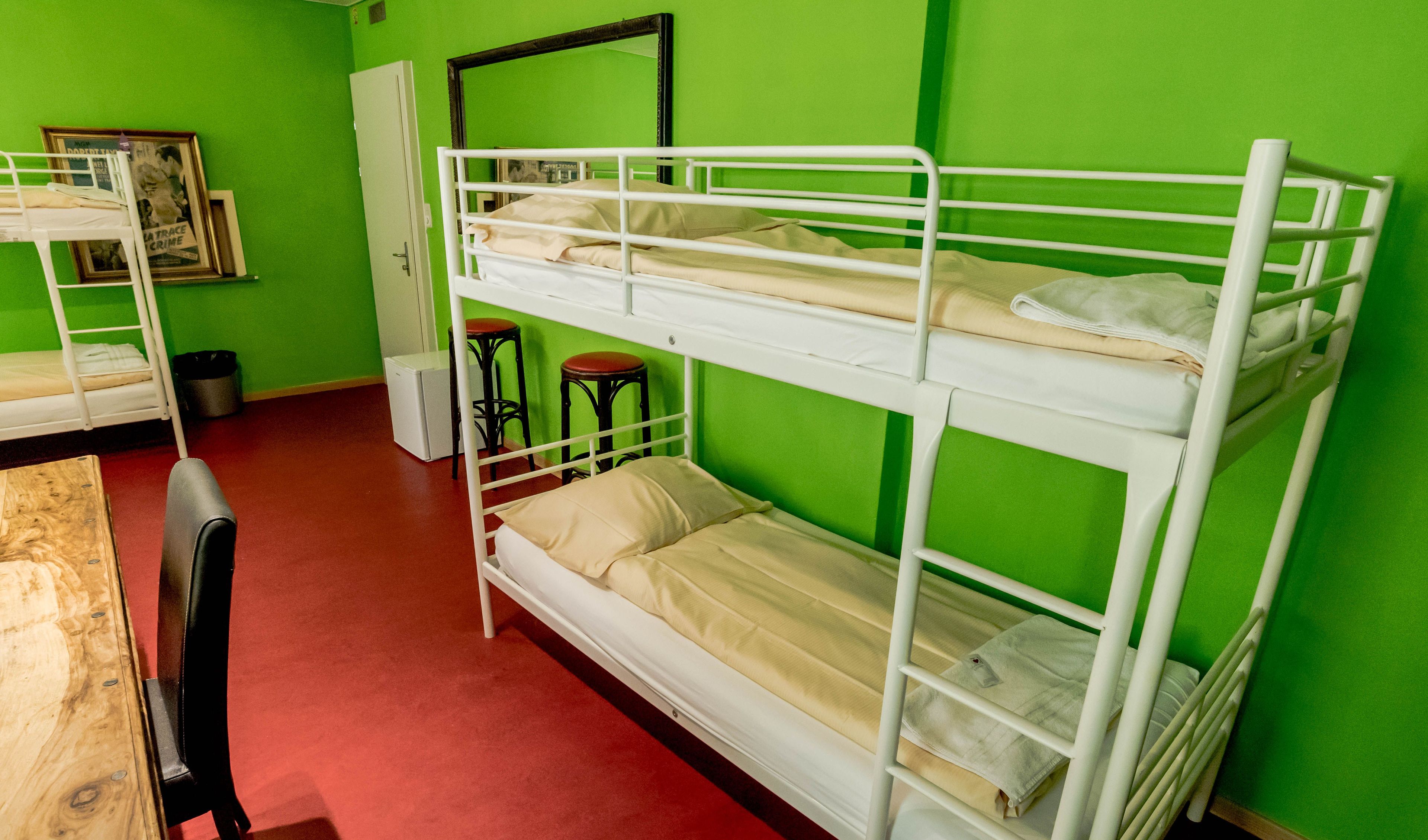 A bunk bed room with green walls, a wooden table, and a chair.