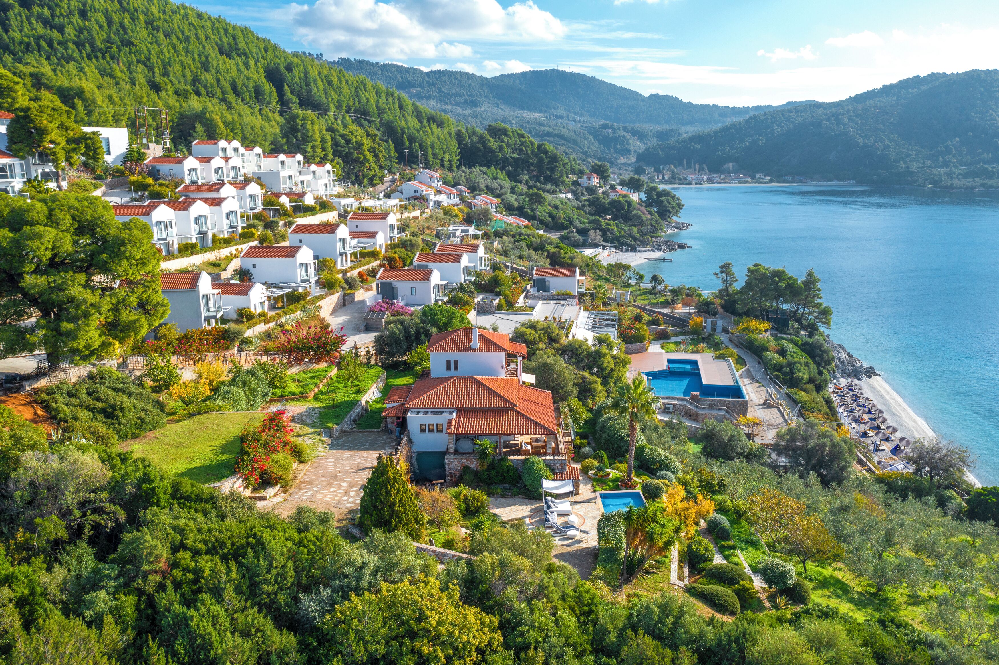 A coastal residential area with houses, a swimming pool, and a beach.