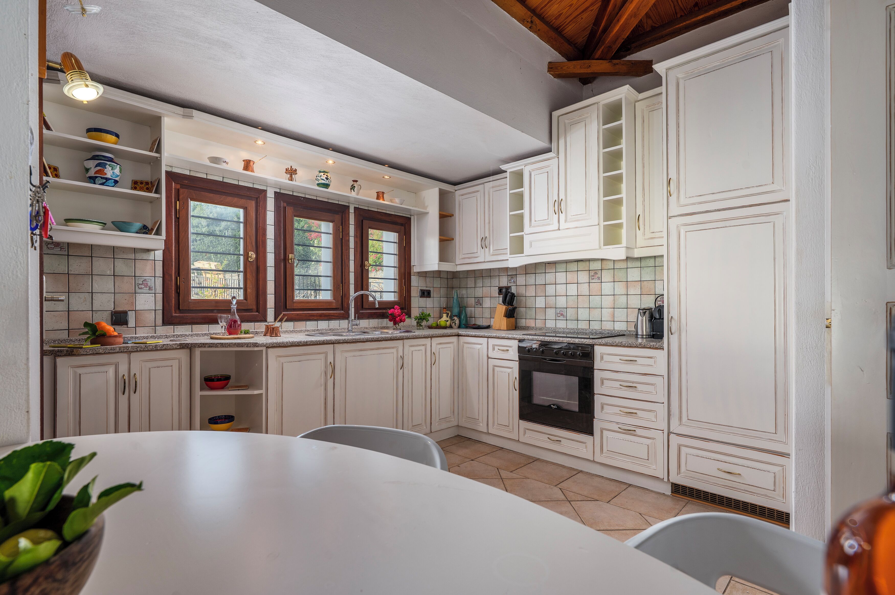 A kitchen with white cabinets, a tiled backsplash, a stove, and a dining area with a table and chairs.