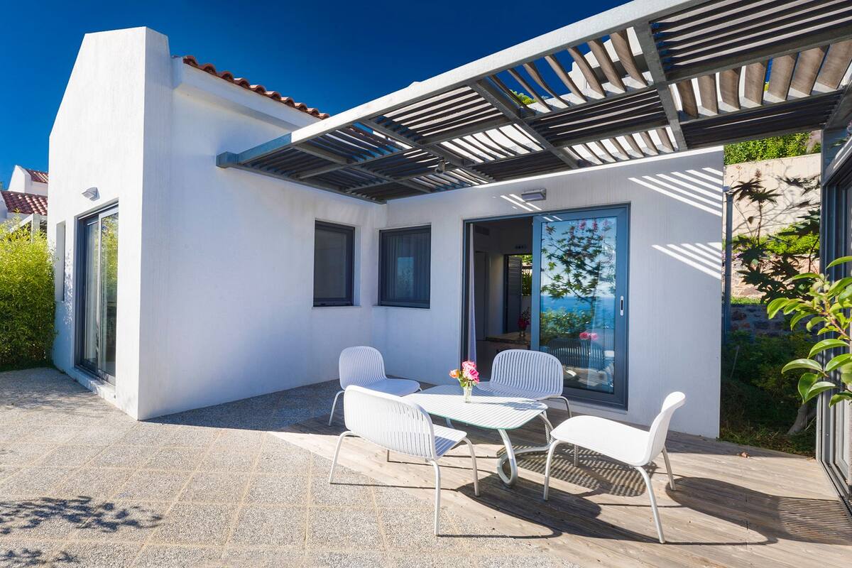 A modern house with a patio, white walls, and a pergola.