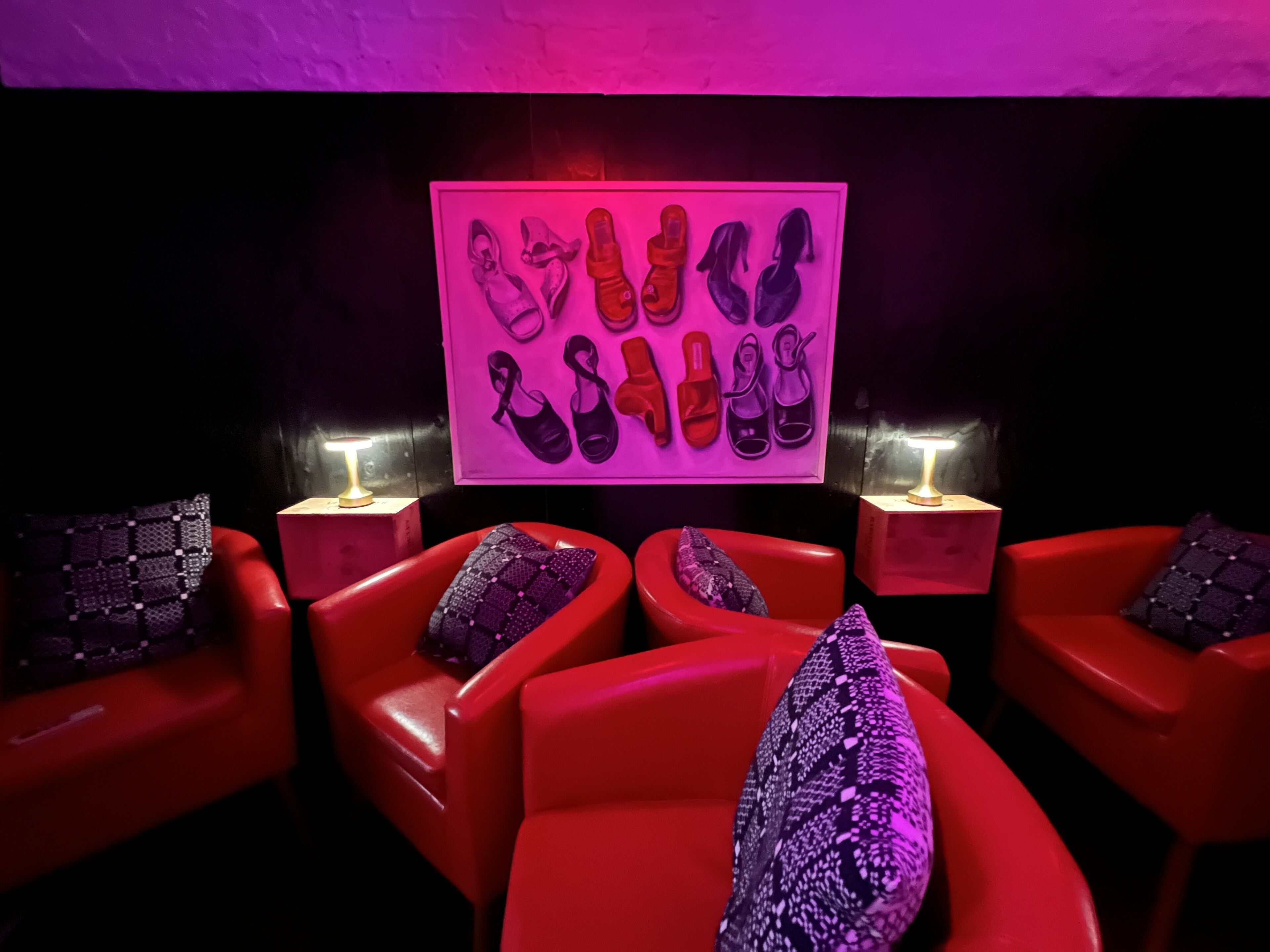 A room with red chairs and a wall-mounted shoe display.
