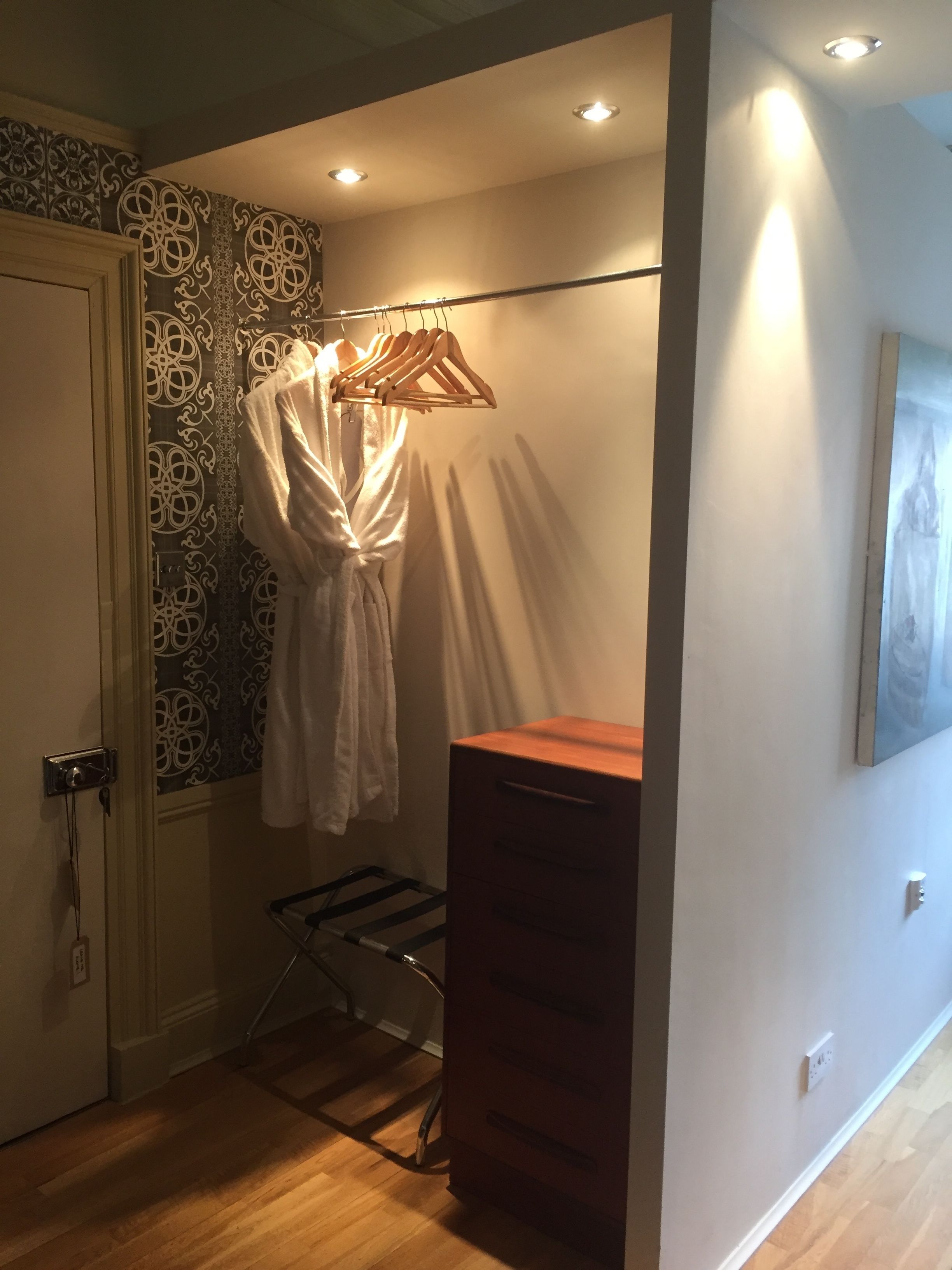 Ein Badezimmer mit Holzboden, einem Handtuchhalter mit weißem Handtuch, einem Holzschrank und wandfarbenem, gemustertem Papier.