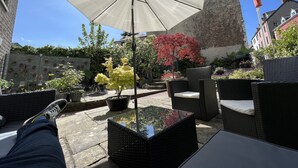 A patio area with outdoor furniture, a large umbrella, and potted plants. - Manorhaus Ruthin (Ruthin)