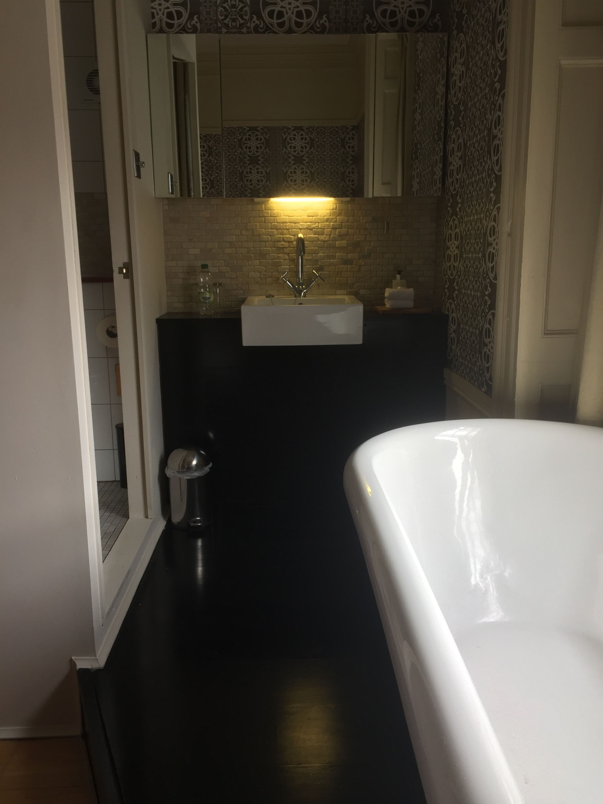 A bathroom with a white bathtub, a sink with a mirror above it, and a towel rack.