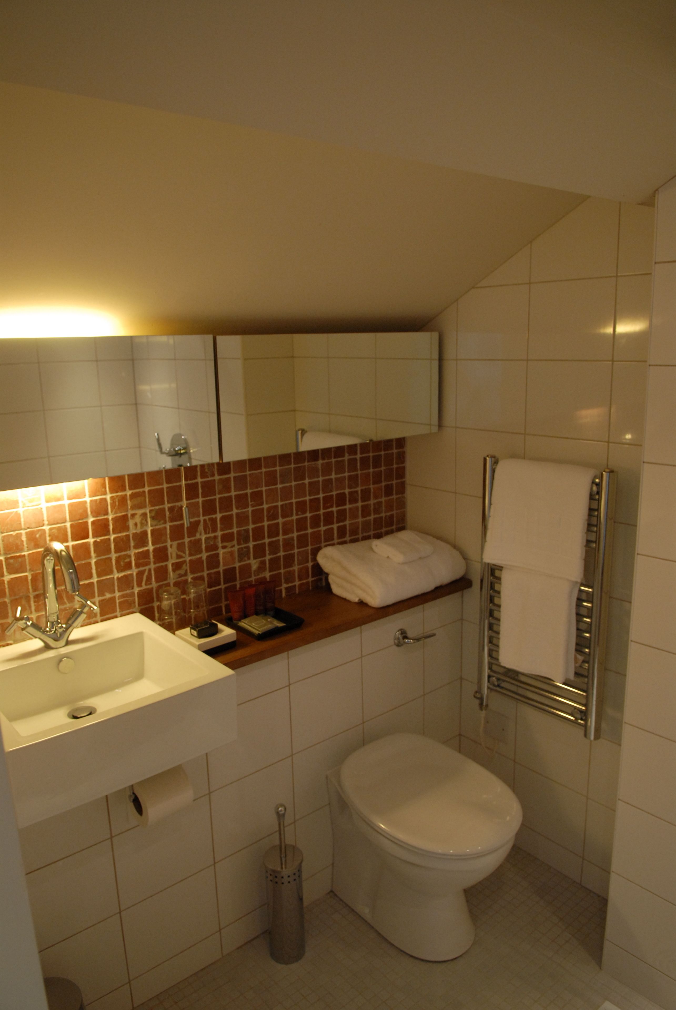 A bathroom with a sink, mirror, toilet, and towel rack.