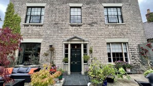 A stone building with a central entrance, large windows, and potted plants around the entrance. - Manorhaus Ruthin (Ruthin)
