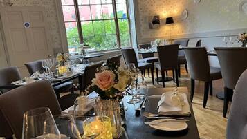 A dining area with tables set for a meal, featuring clear glassware, plates, and cutlery.