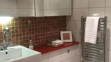 A bathroom with a white sink, a toilet, a mirror, and a towel rack.