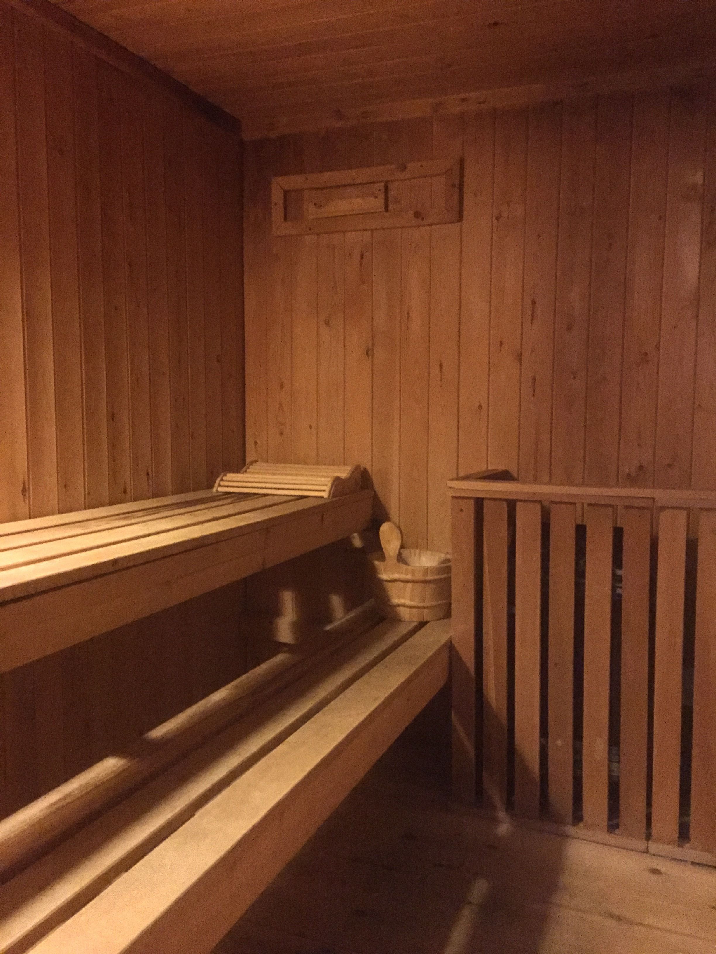 A sauna with wooden benches and a wooden wall.
