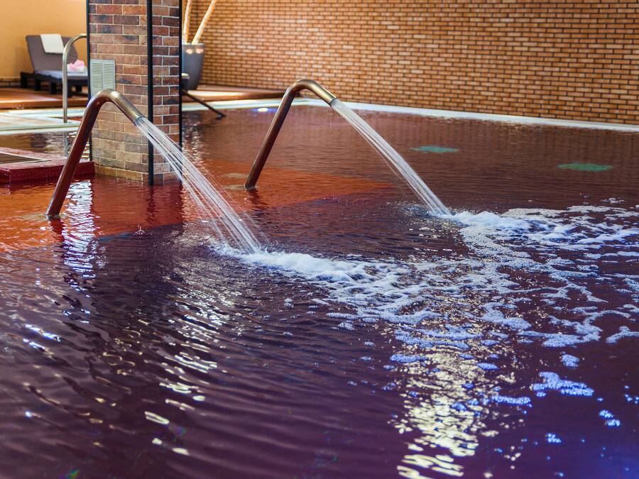 A pool with two metal ladders and a brick wall in the background.